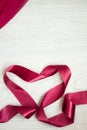 Vertical pink ribbon heart shape on white wooden background. Valentines day and 8 march women day present