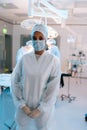 Vertical portrait of African-American female doctor in surgical mask and hat in operating room. Nurse standing posing Royalty Free Stock Photo