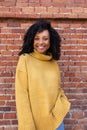 Vertical Portrait Of African American Woman With Curly Hair Wearing Yellow Sweater. Brick Background Wall.