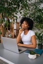 Vertical portrait of attractive African American young woman holding pen in hand, smiling looking at camera sitting at Royalty Free Stock Photo