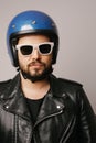 Vertical portrait of bearded biker man in leather jacket and retro blue helmet. Royalty Free Stock Photo