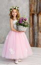 Vertical portrait of a beautiful cute little girl in a wreath of fresh flowers on her head and a basket of beautiful spring Royalty Free Stock Photo