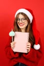 Vertical portrait of a beautiful woman holding a Christmas wish list in her hands on a red background Royalty Free Stock Photo