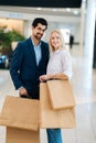 Vertical portrait of beautiful young couple holding shopping paper bags with purchases and looking at camera, standing Royalty Free Stock Photo