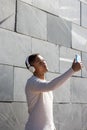 Vertical portrait of black latin guy with headphones taking a selfie on the street with his cell phone Royalty Free Stock Photo