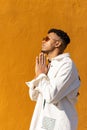 Vertical portrait of a black Latino man with sunglasses praying on a yellow background Royalty Free Stock Photo