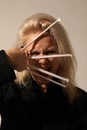 Vertical portrait of blond young woman with white long sticks posing indoor. Royalty Free Stock Photo