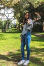 Vertical portrait of a brunette teenage girl looking at camera and pointing fingers in a park Royalty Free Stock Photo