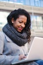 Vertical portrait of business woman watching and typing on a laptop computer outside office. Smiling young female using Royalty Free Stock Photo