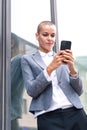 Vertical portrait caucasian business woman using an app on her smartphone outdoors. Royalty Free Stock Photo