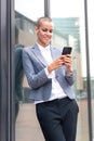 Vertical portrait caucasian business woman using an app on her smartphone outdoors. Royalty Free Stock Photo