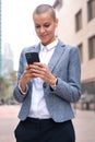 Vertical portrait caucasian business woman using an app on her smartphone outdoors. Royalty Free Stock Photo