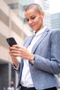 Vertical portrait caucasian business woman using an app on her smartphone outdoors. Royalty Free Stock Photo