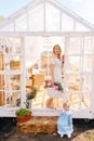 Vertical portrait of charming blonde young woman in dress standing on doorstep of summer gazebo house with adorable Royalty Free Stock Photo