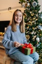 Vertical portrait of cheerful adorable little girl holding wrapped with red ribbon and bow festive Christmas present Royalty Free Stock Photo