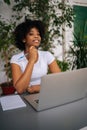 Vertical portrait of confident curly African female student woman holding pen in hand, smiling looking at camera sitting Royalty Free Stock Photo