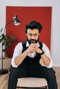 Vertical portrait of confident handsome businessman wearing elegant formalwear sitting on soft chair and looking at Royalty Free Stock Photo