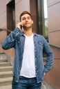 Vertical portrait of confident handsome young man talking on mobile phone standing on stairs of modern office building Royalty Free Stock Photo