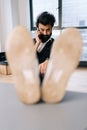 Vertical portrait of confident Indian businessman talking on smartphone sitting with feet on table in office, looking at Royalty Free Stock Photo