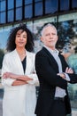 Vertical portrait of crossed arms business people looking at camera with successful expression. Couple of multiracial Royalty Free Stock Photo