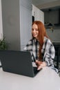 Vertical portrait of cute freelancer female working typing on laptop computer sitting at table, smiling looking to Royalty Free Stock Photo