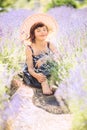 Vertical portrait dreamy cute little girl with haircut in big summer hat in lavender field with purple flowers around in sunny sum