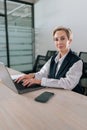 Vertical portrait of elegance gray-haired middle-aged business woman using laptop computer sitting at workplace desk. Royalty Free Stock Photo