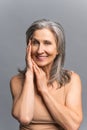 Fascinating attractive mature gray-haired woman look at the camera over grey
