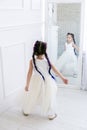 Vertical portrait of a five year old girl standing in front of a mirror in a white studio Royalty Free Stock Photo