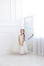 Vertical portrait of a five year old girl in a white dress who is spinning near the mirror in a white studio Royalty Free Stock Photo