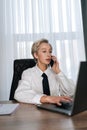 Vertical portrait of focused businesswoman talking phone typing laptop multitask in office. Portrait of busy female