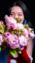 Vertical portrait of a girl with blue-colored hair hiding behind a bucket of roses