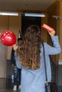 Vertical portrait of girl waiting for her boyfriend in the doorway of her house to surprise him with a gift and a balloon to Royalty Free Stock Photo