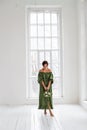 Vertical portrait of a girl in a white studio against the background of a huge window