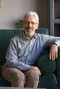 Vertical portrait of grey haired mature man sitting on couch Royalty Free Stock Photo