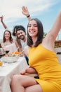 Vertical portrait of a group of young adult friends having fun and laughing on a dinner party rooftop. Happy multiracial Royalty Free Stock Photo