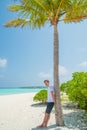 Vertical portrait of handsome attractive man wearing t-shirt and shorts at tropical beach at island luxury resort Royalty Free Stock Photo