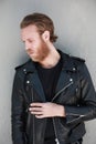 Vertical portrait of handsome bearded man, wearing biker leather jacket. Posing outdoor.