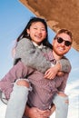 Vertical portrait of handsome boyfriend with sunglasses giving a piggyback ride to his joyful girlfriend. Young Royalty Free Stock Photo