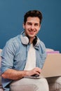 Vertical portrait of handsome entrepreneur freelancer man working at home with a laptop sitting on a couch smiling and Royalty Free Stock Photo