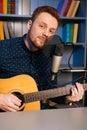 Vertical portrait of handsome guitarist singer man playing on acoustic guitar and singing into microphone recording song Royalty Free Stock Photo