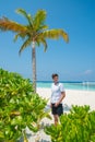 Vertical portrait of handsome man wearing white t-shirt on the tropical beach at the island luxury resort Royalty Free Stock Photo