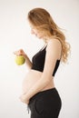 Vertical portrait of handsome young light-haired european pregnant woman in black outfit, staying in profile, holding Royalty Free Stock Photo