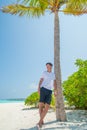 Vertical portrait of handsome young man wearing white t-shirt on the tropical beach at the island luxury resort Royalty Free Stock Photo