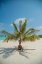 Vertical portrait of handsome young tanned man resting under palm tree at the beach at the tropical island luxury resort Royalty Free Stock Photo