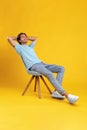 Happy guy relaxing sitting on chair, leaning back at studio Royalty Free Stock Photo