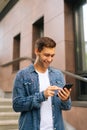 Vertical portrait of happy handsome young man using mobile phone standing on stairs of modern office building. Royalty Free Stock Photo