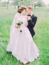 Vertical portrait of the happy newlywed couple standing head-to-head at the background of the green field. Royalty Free Stock Photo