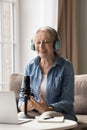 Vertical portrait happy 65s woman in headphones speaks into microphone Royalty Free Stock Photo