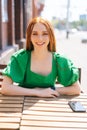 Vertical portrait of happy smiling young woman sitting at table in outdoor cafe terrace in sunny summer day and looking Royalty Free Stock Photo